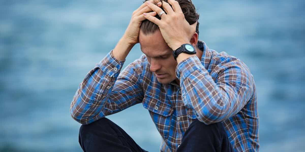Come il Respiro Originario Può Aiutare a Gestire l’Ansia Uomo stressato che gestisce l'ansia con il Respiro Originario vicino al mare