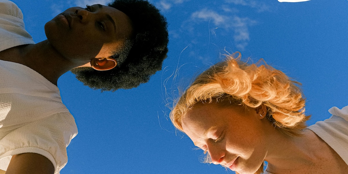 Respiro Originario: Benefici per la Salute Mentale Due persone praticano il Respiro Originario all'aperto sotto un cielo azzurro